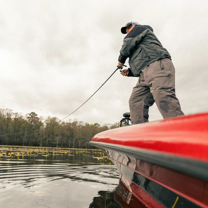 collins_illich_f5djb4rhfjs_unsplash_1 Low angle image of a fisherman standing on a boat with his line in the water.