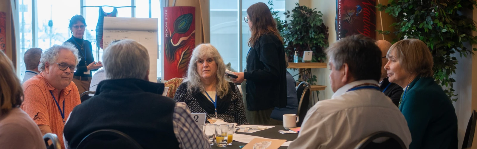 A group of men and women sitting at a round table at a conference in conversation