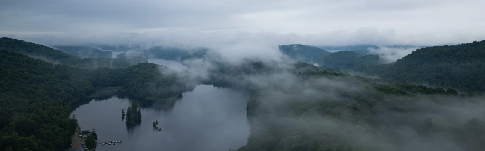 Misty scene from above of a bay below and hills surrounding it